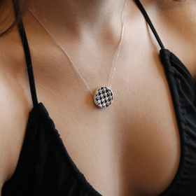 silver double-sided necklace with neon and black enamel houndstooth pattern